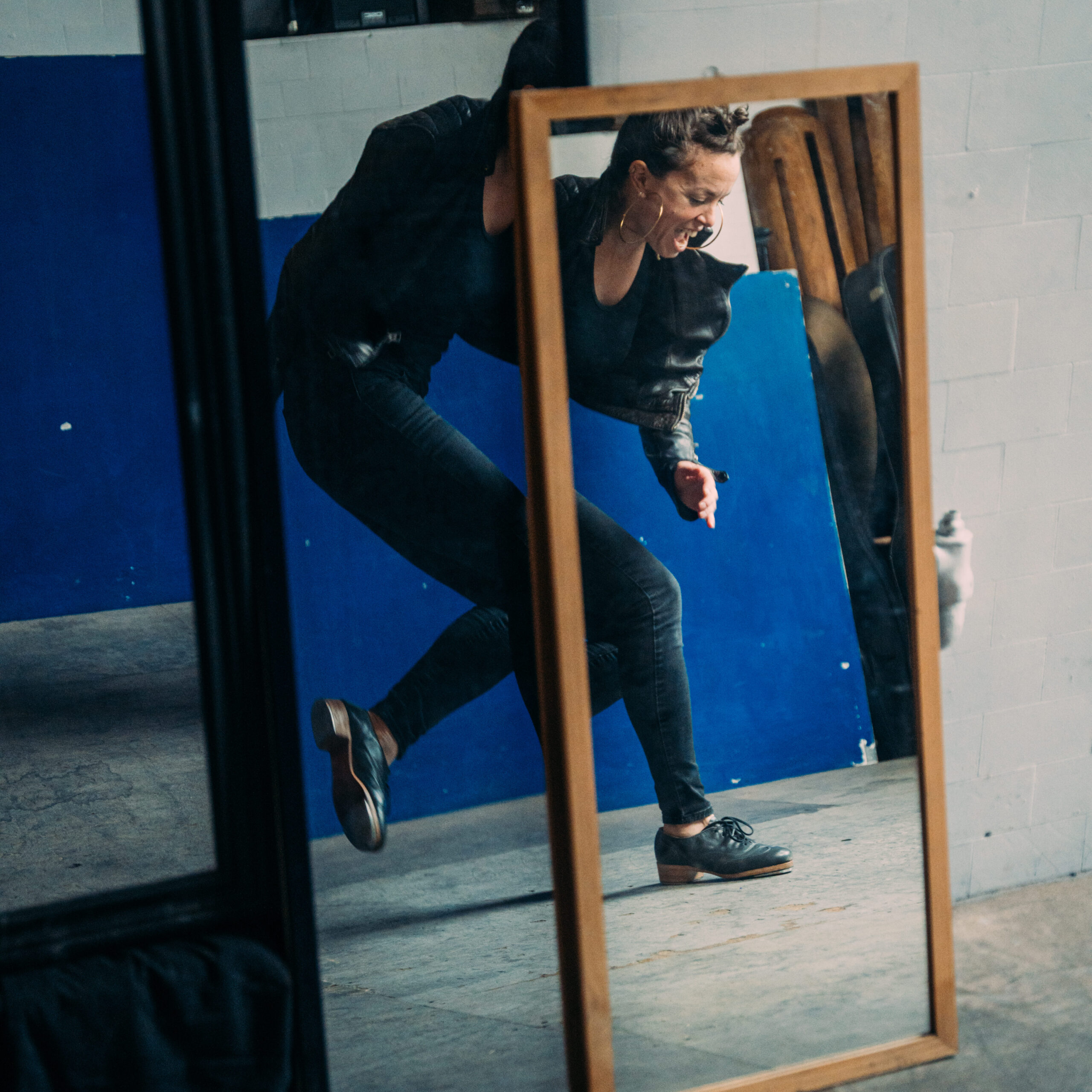 a female tap dancer's reflection in two mirrors stacked on top of each other