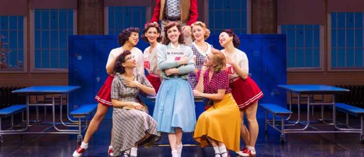 a group of performers huddled together around a table on stage