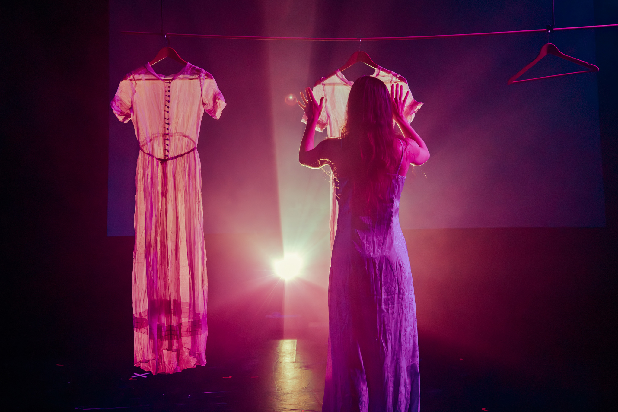 a female dancer hanging up a white dress on stage