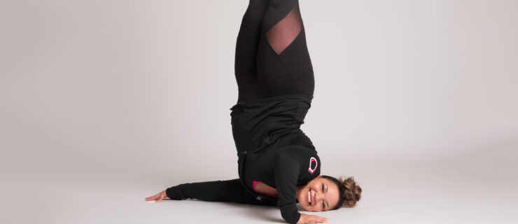 a female dancer wearing black balancing on her shoulder with her legs straight up