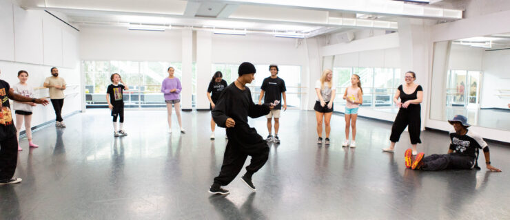 a male instructor teaching hip hop to students in a large studio