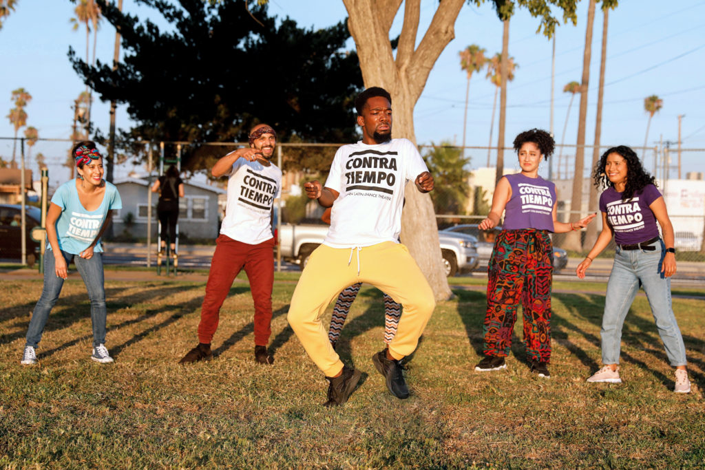 a group of dancers moving in a park