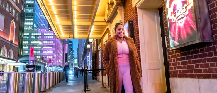 female wearing pink athletic clothes and brown jacket walking down the street