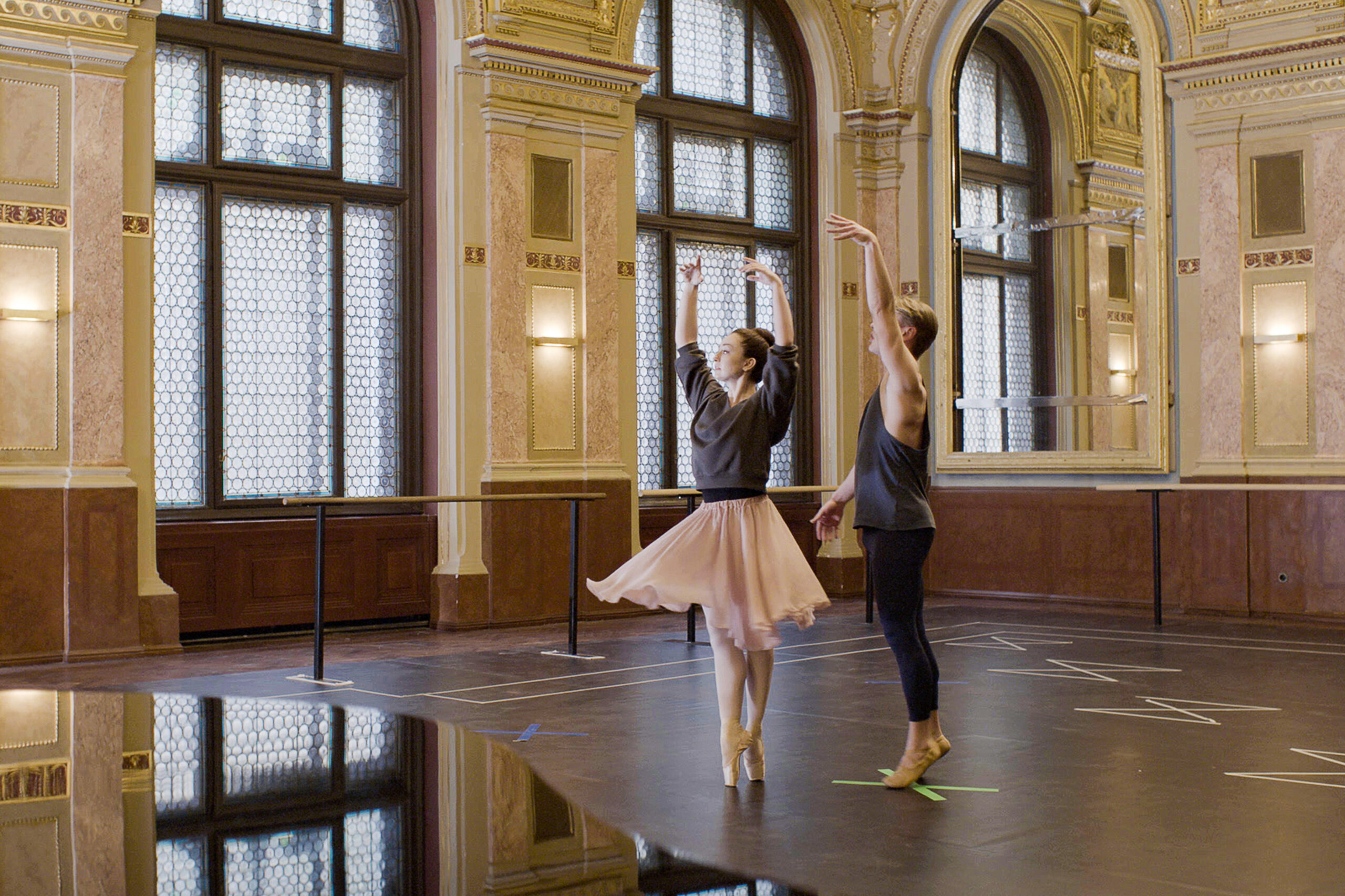 In a still from "FBI: International," Madison Keesler poses in sous-sus on pointe, arms in high fifth. Her partner stands just behind her, one arm upraised as though he had just released her hands. They were practice clothes and are in a beautiful studio, a piano visible in the foreground.