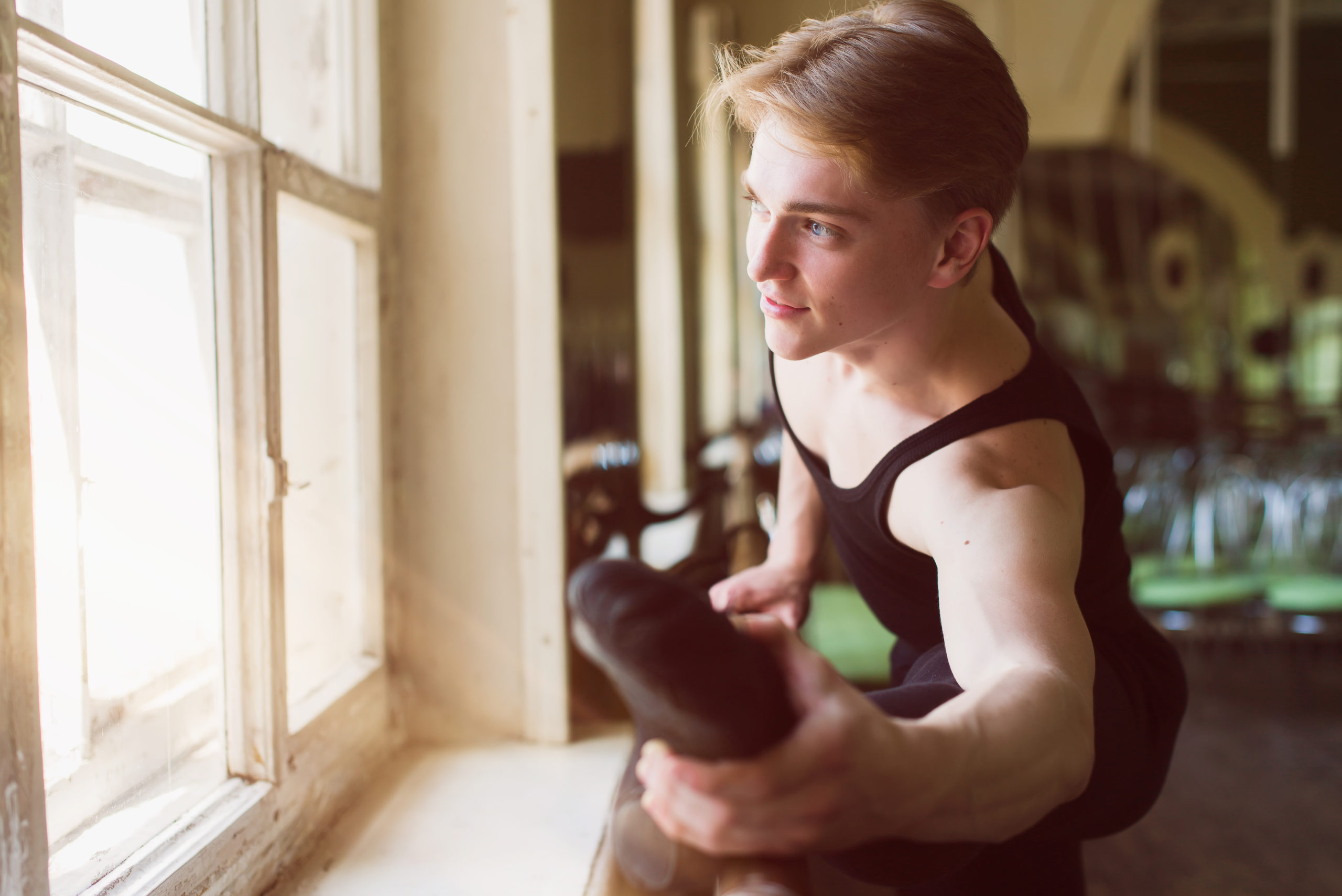 Male ballet dancer stretching at ballet barre, close-up of foot