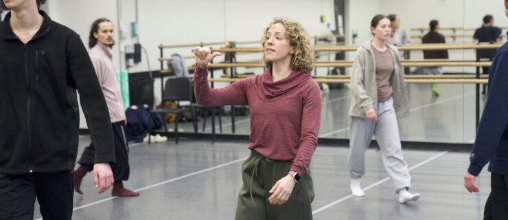 a female instructor motioning in a studio while leading students