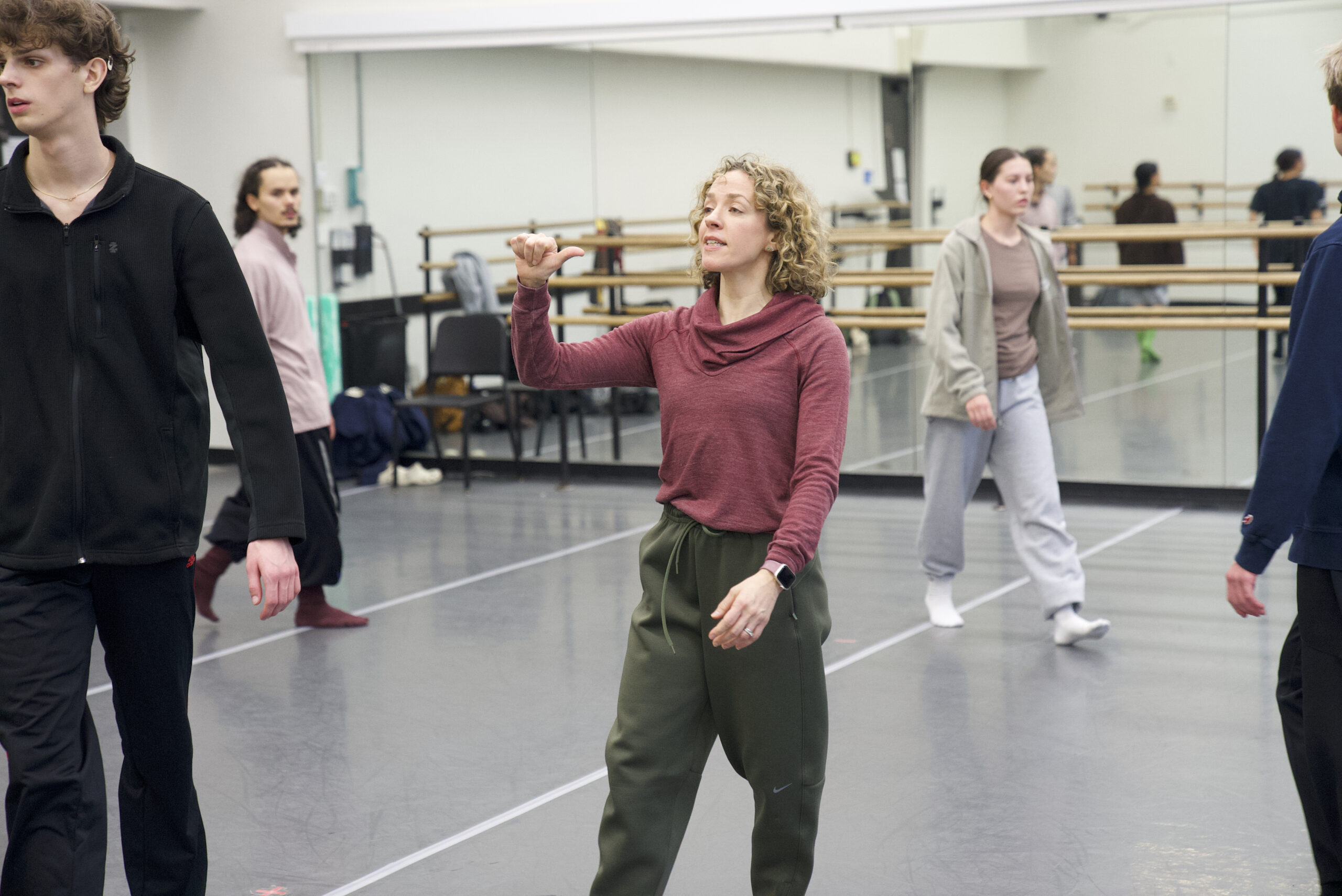 a female instructor motioning in a studio while leading students