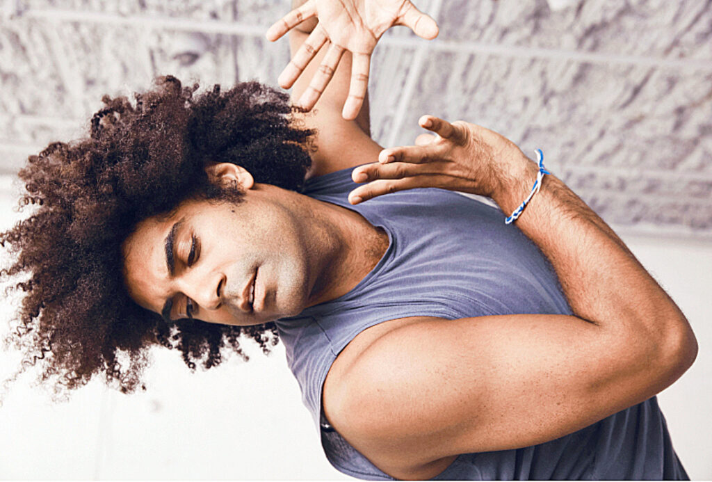 male dancer wearing tank top and pushing arms away