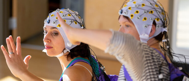 two women moving together wearing tight caps with wires attached to them