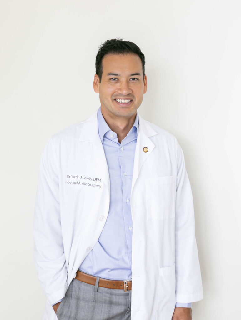 a man with dark hair wearing a white coat smiling at the camera