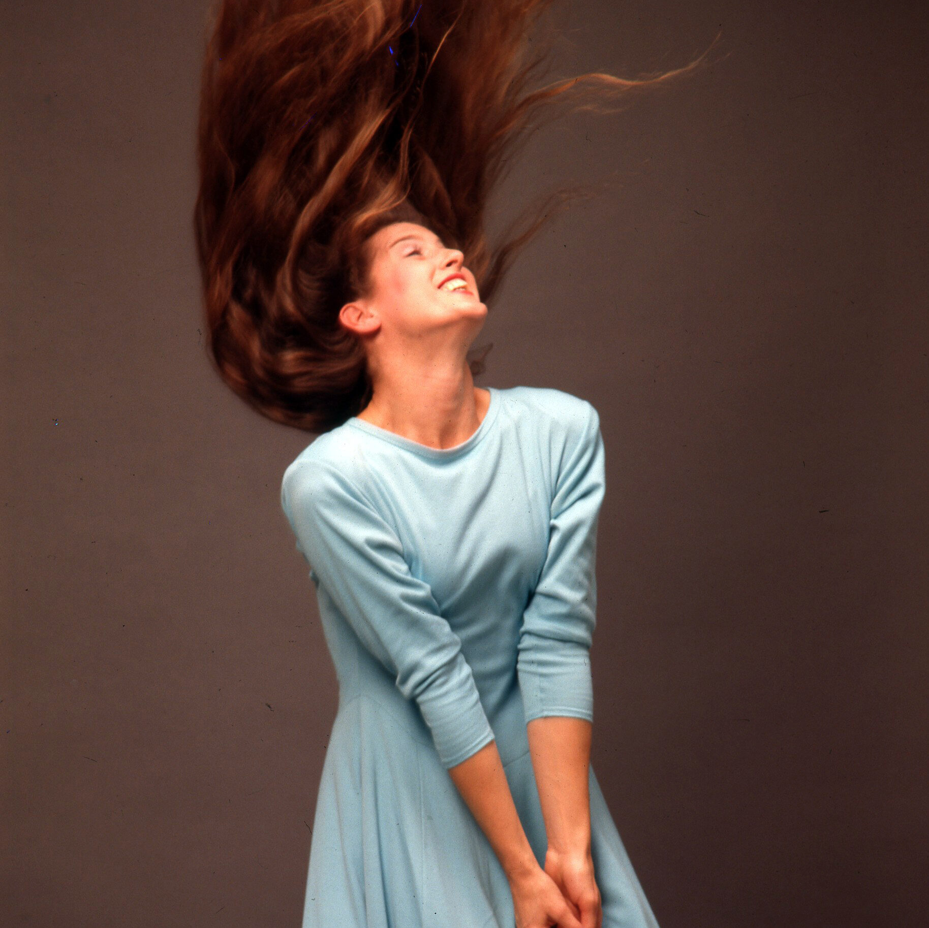 a female dancer wearing blue flipping her hair up while smiling 