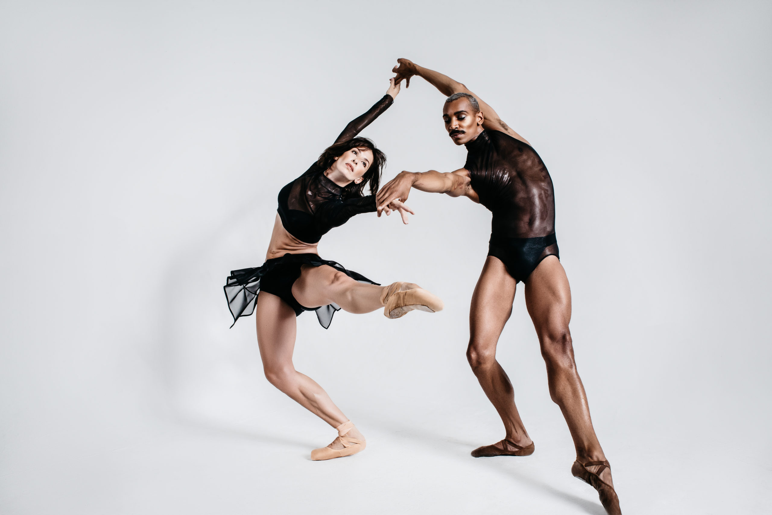 man and woman dancing, man is wearing black leotard, woman is wearing black tutu and crop top