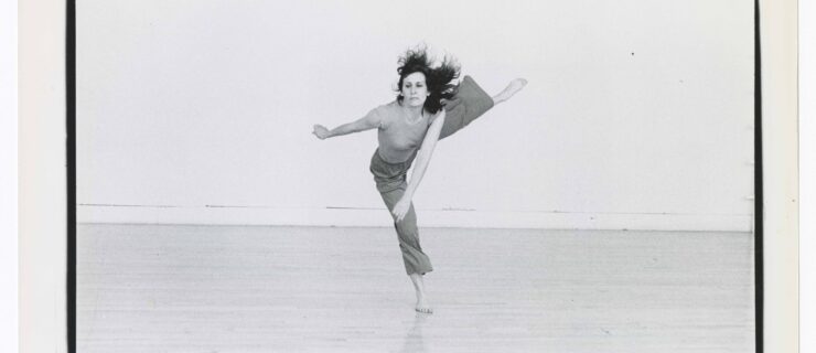 a female dancer in a black and white photo lifting her leg directly side and swinging her arms in opposition